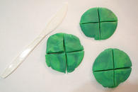 Three circular 'pancakes' made of modelling dough, each divided into four equal parts.